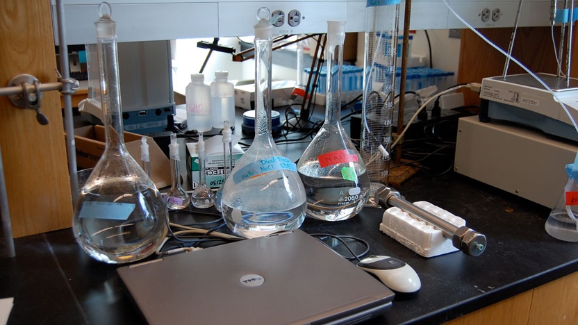 Image of tubes, beakers, and a computer laptop in a science lab.