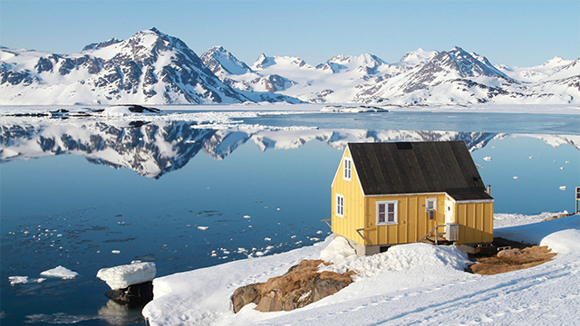 Snowy scenic scene of a yellow cabin on the water