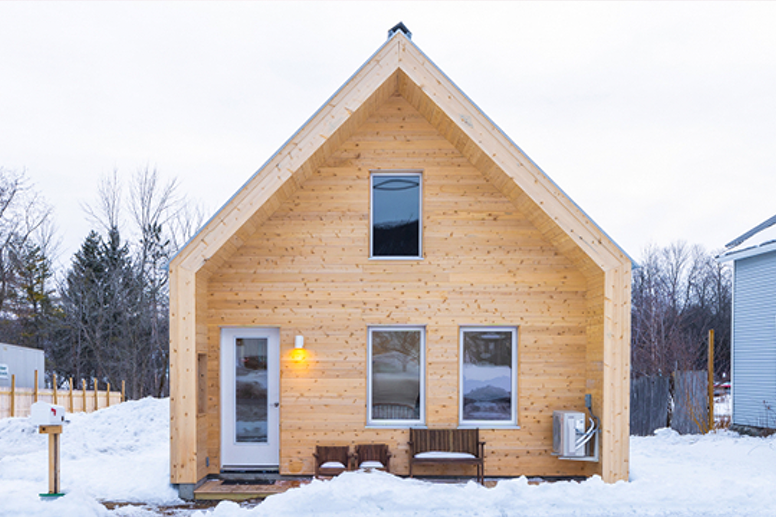 a Habitat for Humanity house with light wood siding, surrounded by a snowy yard.