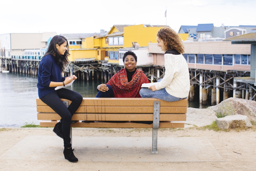 Three women sitting on the pier in Monterey