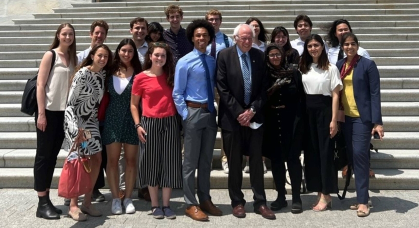 A group of Middlebury students and staff standing on the Capitol steps with Bernie Sanders.
