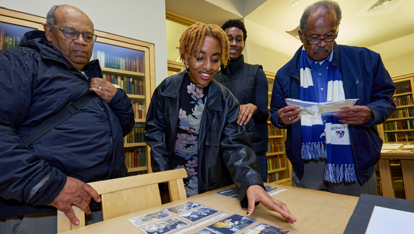 Past and present members of the Black Student Union look over archival photos and documents in the library.