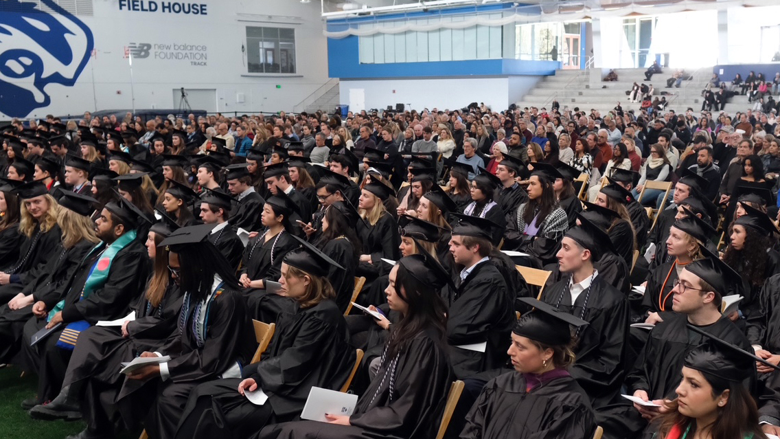 Students in caps and gowns sit in their seats for a graduation ceremomy
