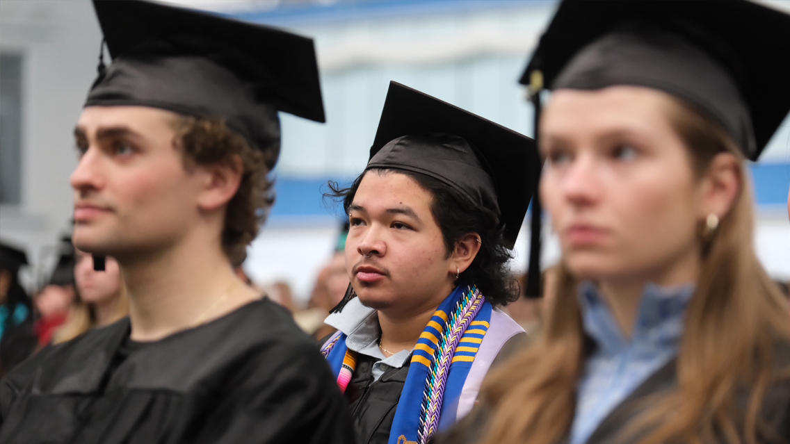 Students in caps and gowns smiling at ceremony