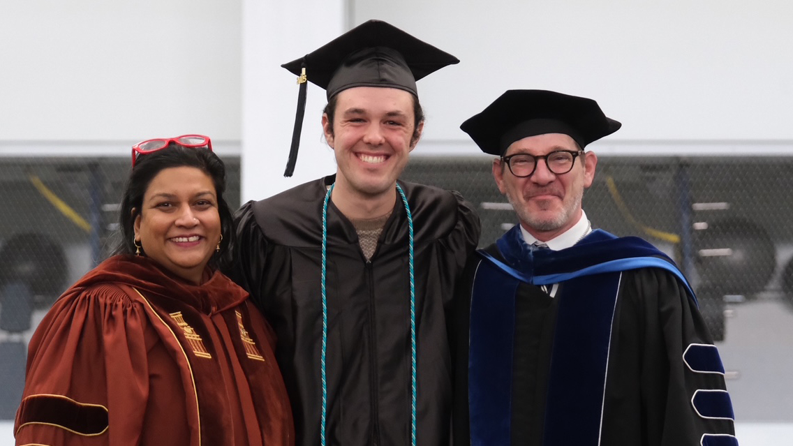 Three people in caps and gowns pose for a picture