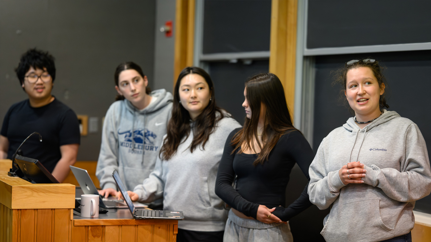 Five students stand at a podium as they give a presentation.