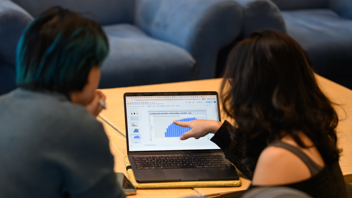 Two students focus on a laptop in preparation for a presentation.