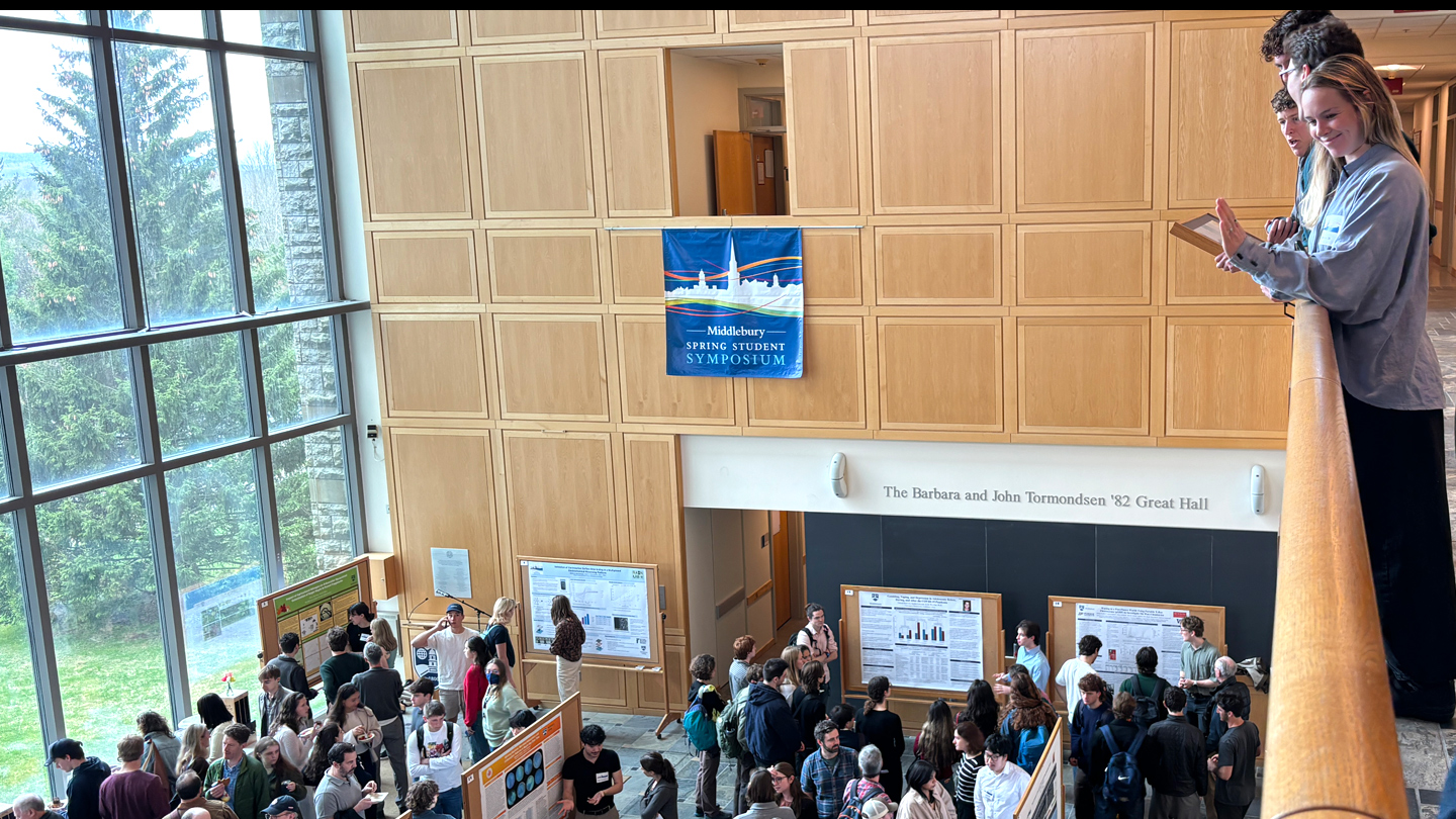 A student waves to a friend in the crowd at a busy poster session.