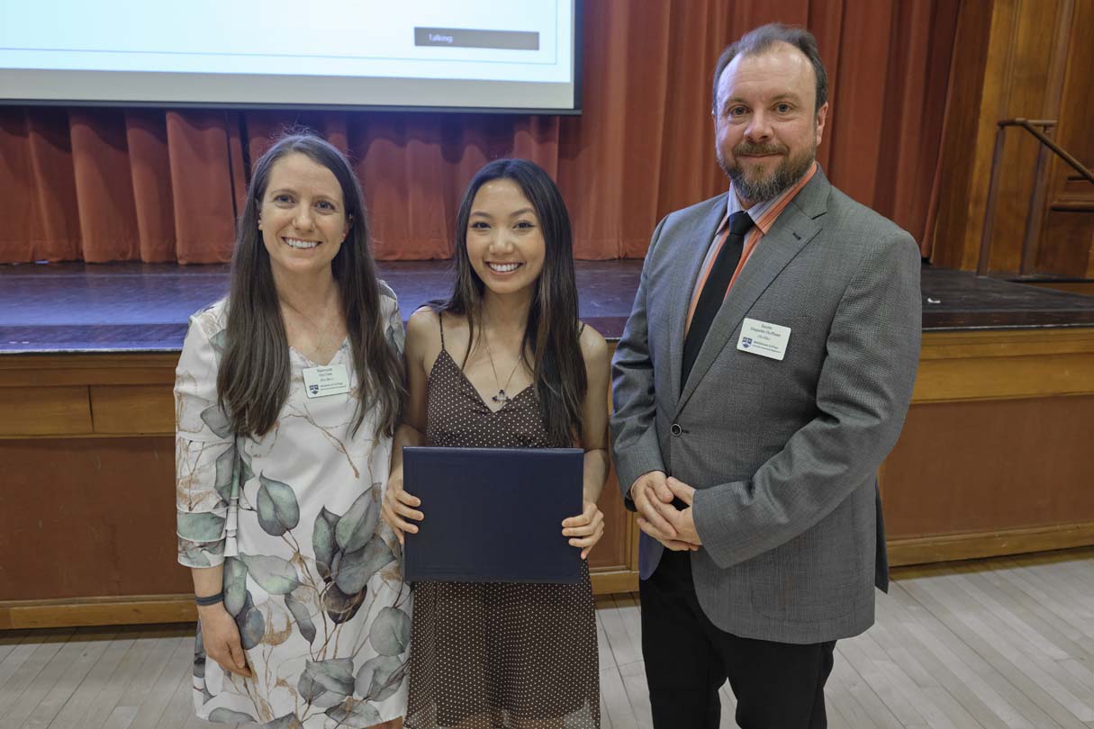 Three people pose for a photo during an awards ceremony.