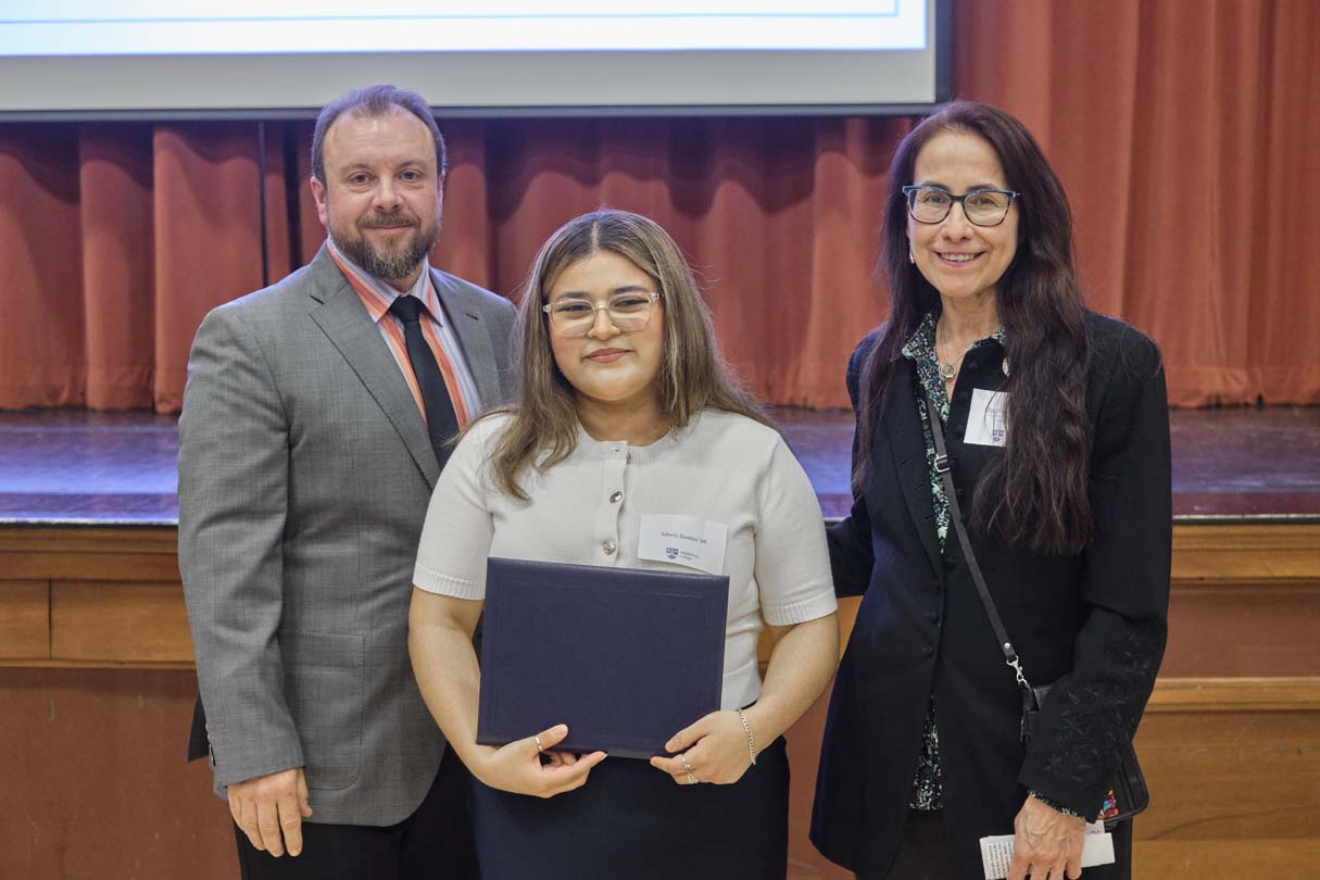 Three people pose for a photo during an awards ceremony.