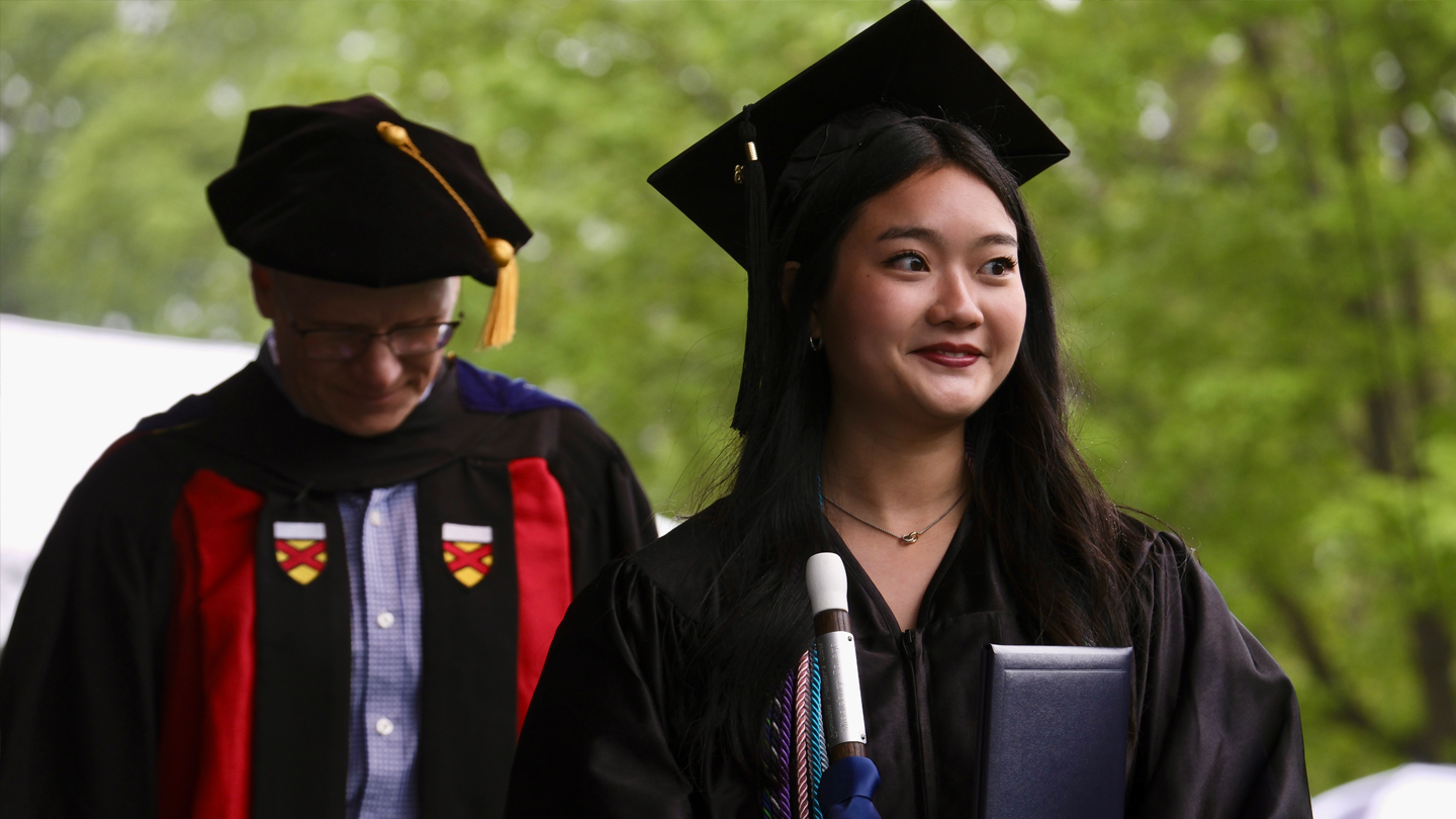 Student in academic regalia crosses the stage