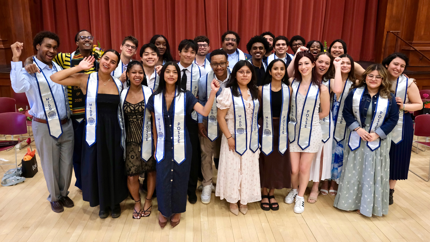A group of students wearing Posse banners poses for a photo in front of a curtain.