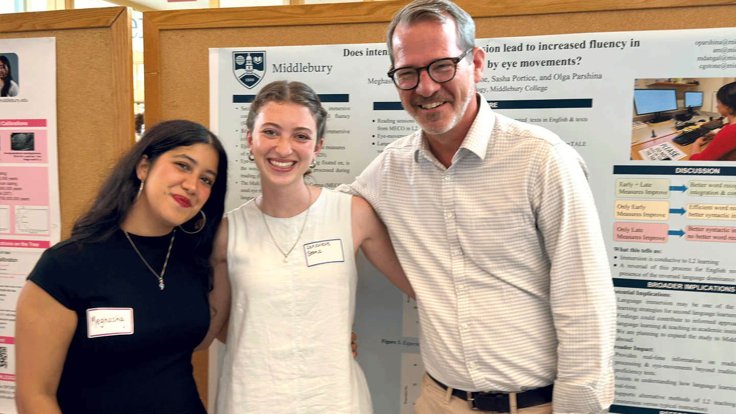 President Ian Baucom and two students smile for the camera during a poster session for the summer research symposium.