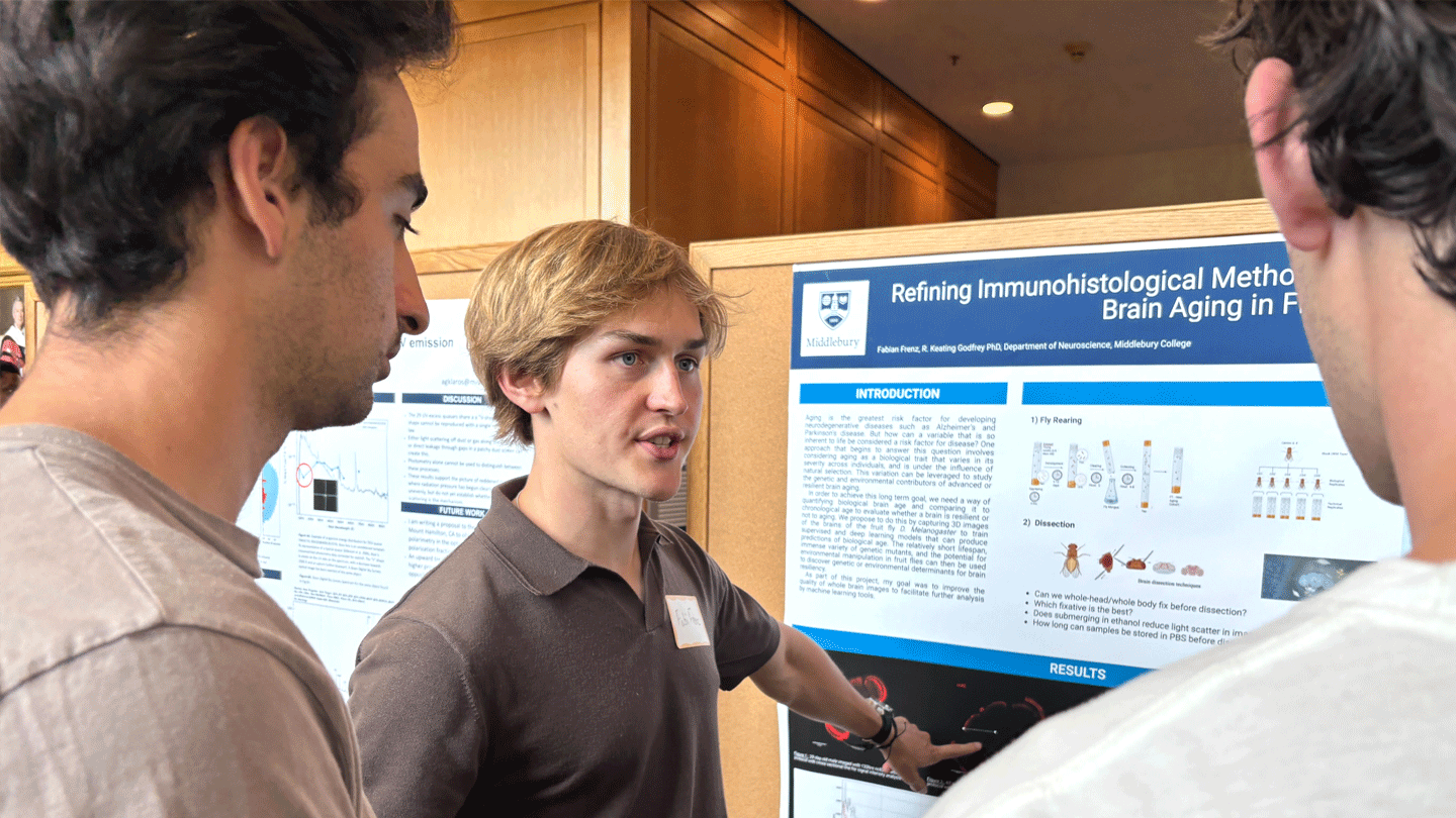 A student explains their summer research project at a poster session in McCardell Bicentennial Hall.