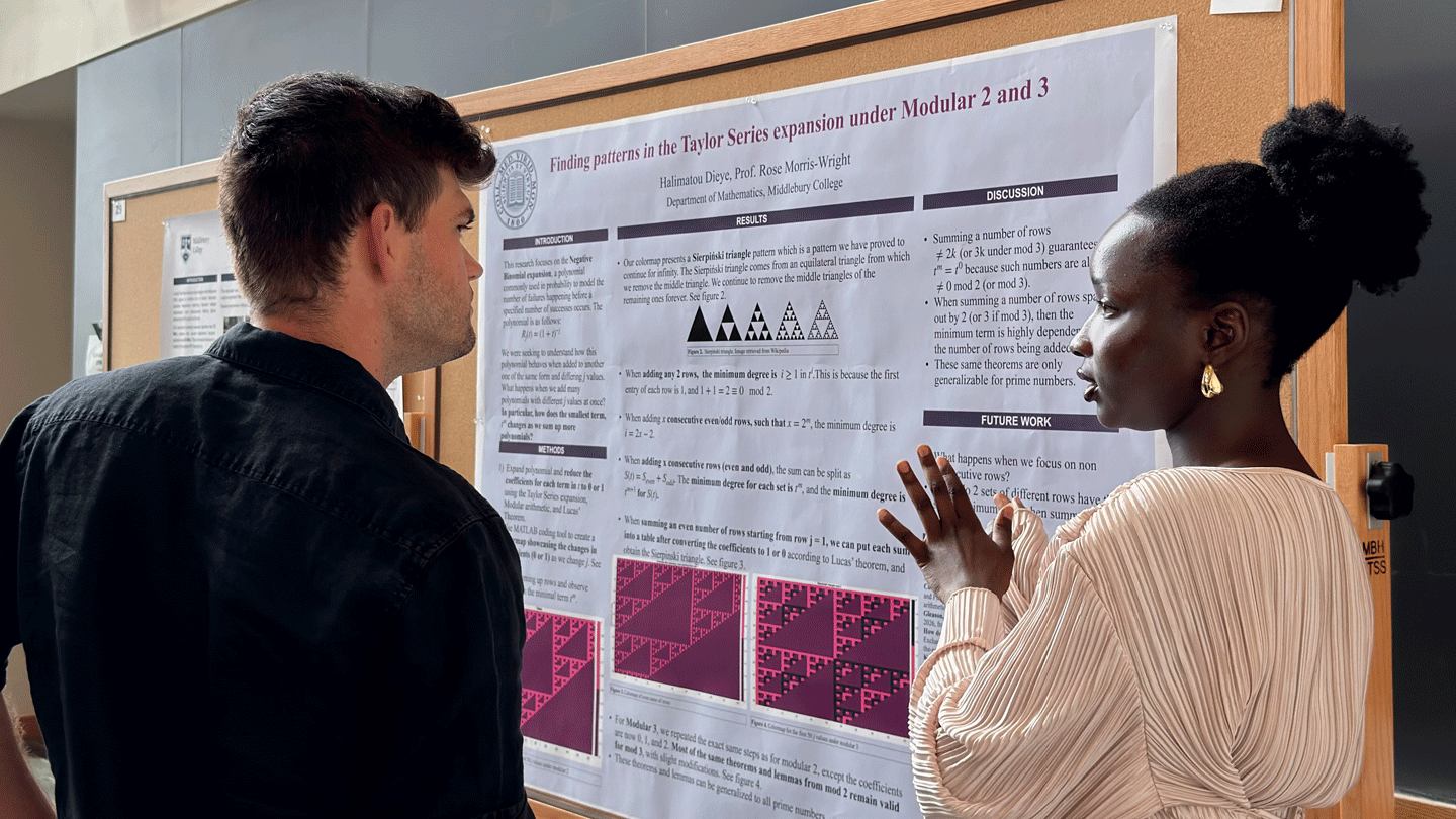 A student explains their summer research project at a poster session in McCardell Bicentennial Hall.