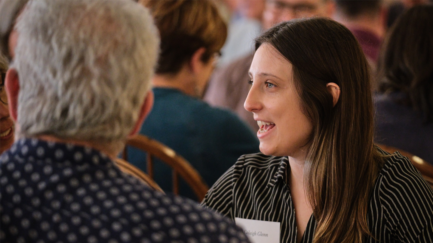 A professor engages in a small group discussion at a table.