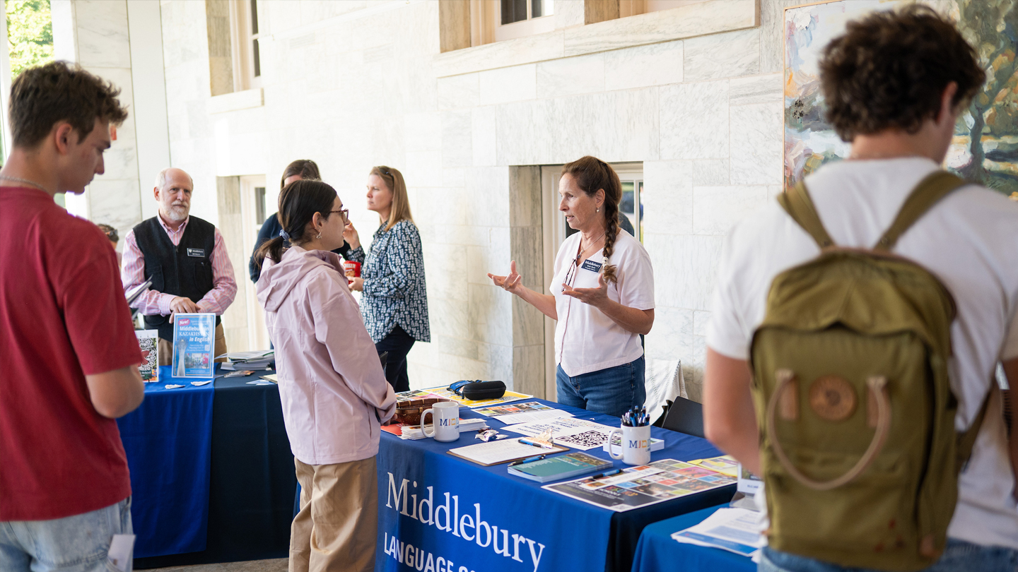 Students speak with staff across a table during a study abroad fair.