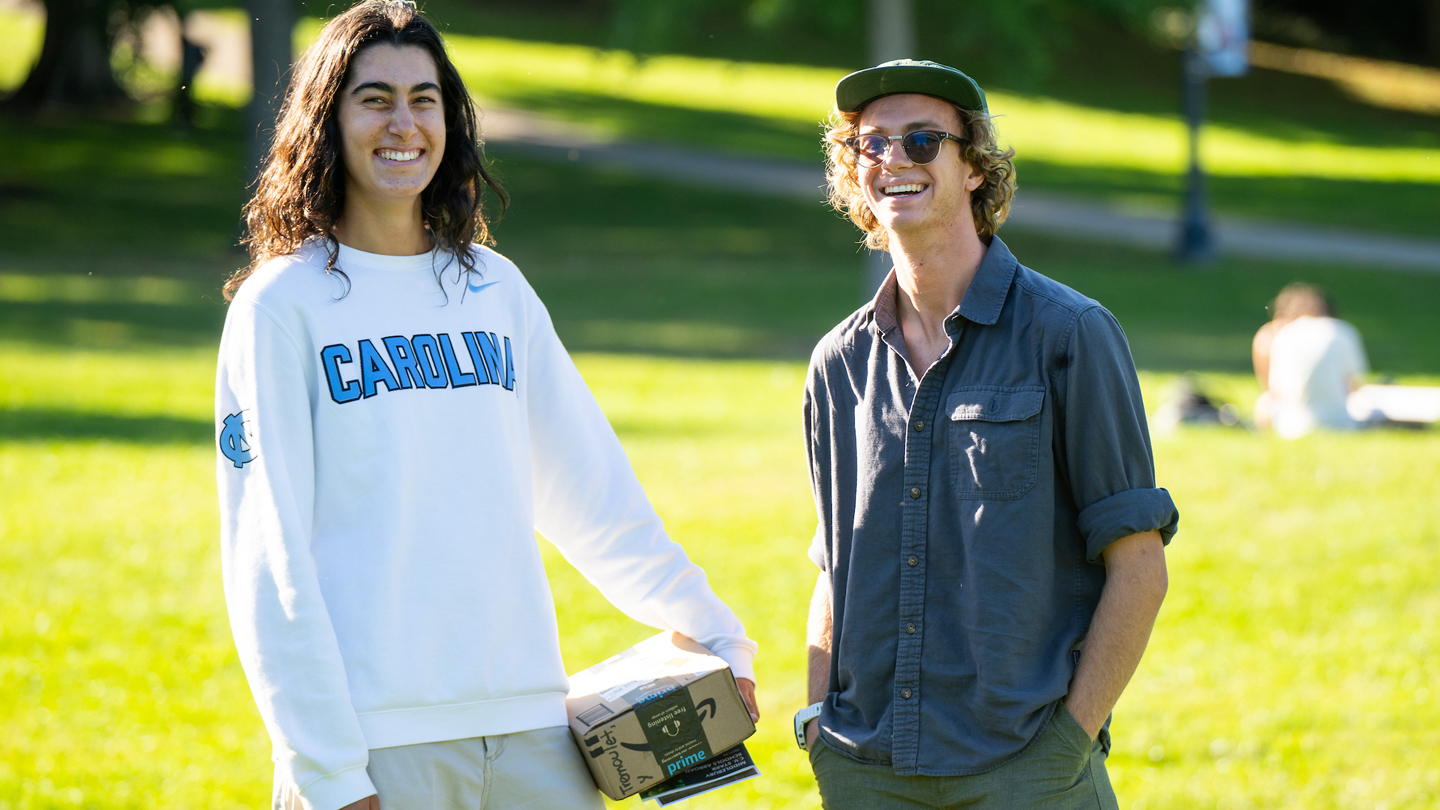 Two students smile at the camera outside.