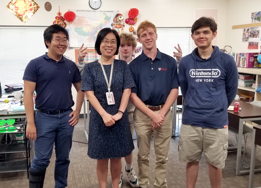 A teacher stands with her students in a classroom.