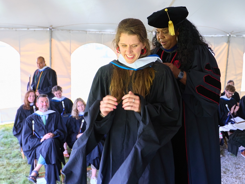A master's student receives her hood at Commencement ceremony.