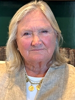 head shot of woman with white shirt, gold necklace, and tan jacket