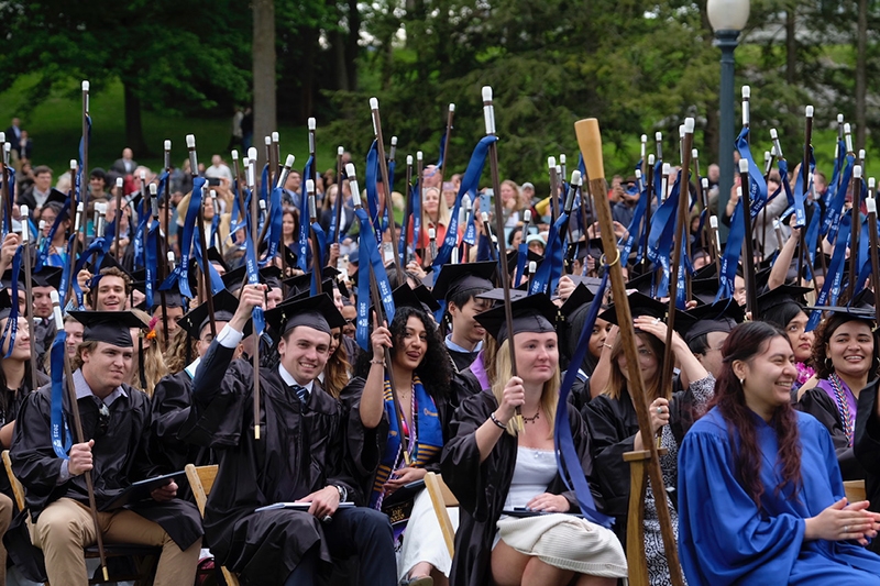 A group of Middlebury graduates raise their canes in the air.