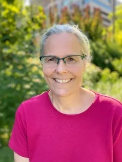 Woman in bright pink shirt smiles at the camera.