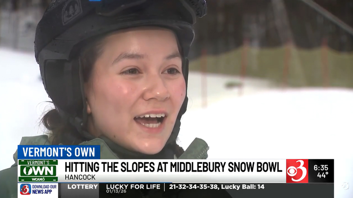 Student wearing ski gear speaks to an interviewer on a snowy hill.