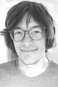 Photo of student wearing glasses and t-shirt smiling at camera.