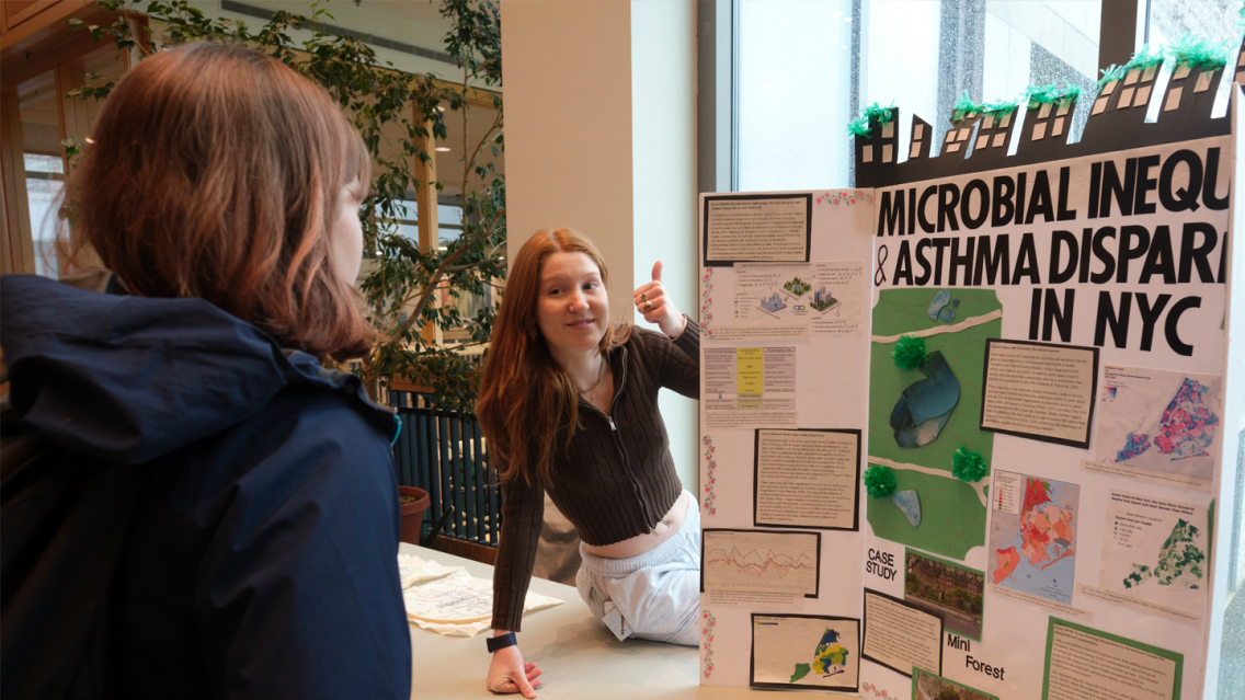 Two students talk at a science poster presentation.