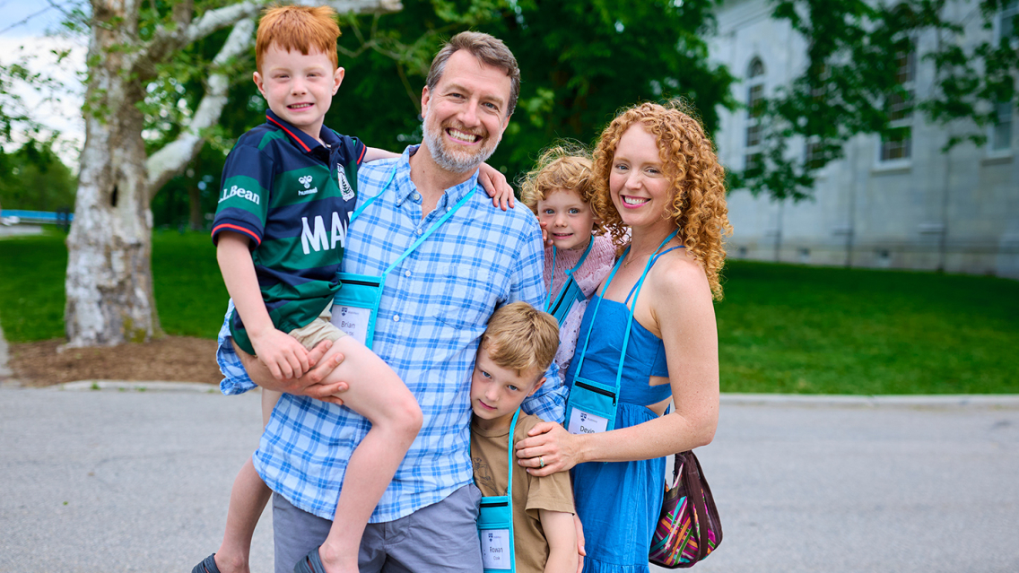 A family with three kids smiles for a photo on campus at Reunion.