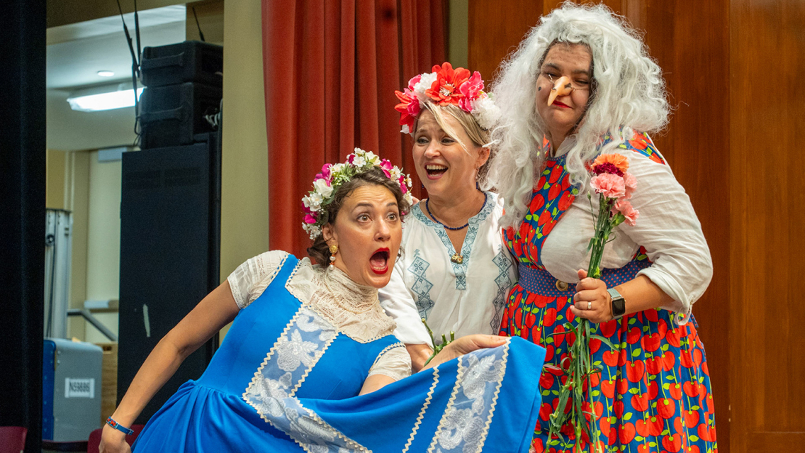 Actors in a Language Schools play pose for a photo in colorful costumes.