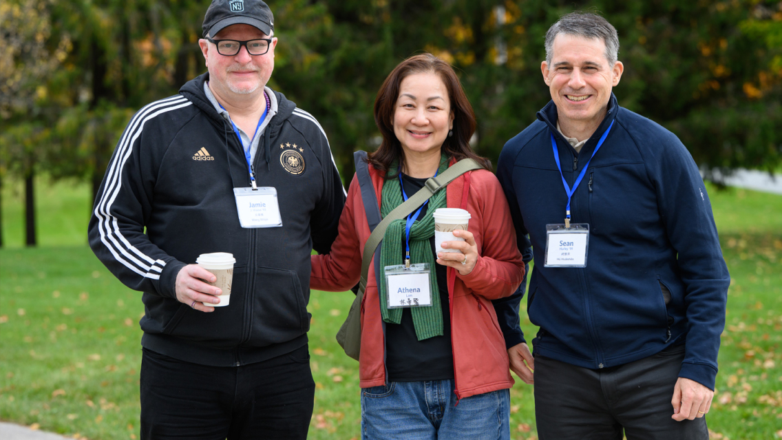 Alumni from the Middlebury Chinese department hold coffee cups and smile during a reunion at the Bread Loaf campus.