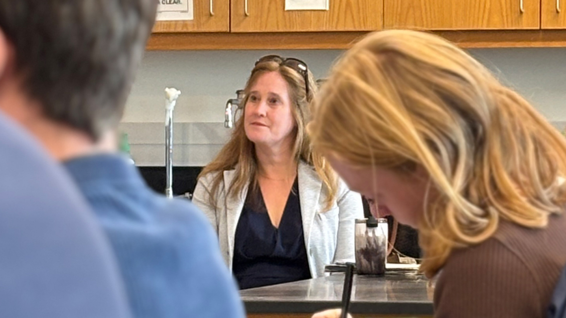 A Middlebury professor sits in a classroom listening to a guest speaker.