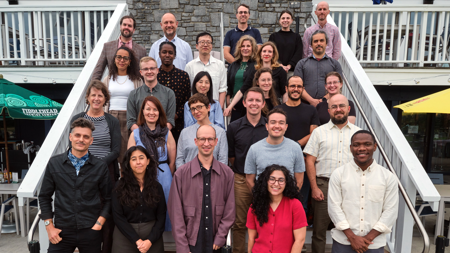 A group of Middlebury faculty members pose for a photo on an outdoor staircase.
