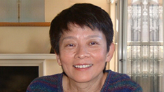 Headshot of woman wearing a dark striped sweater and smiling.