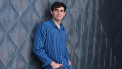Photo of a student standing against a textured wall outside.