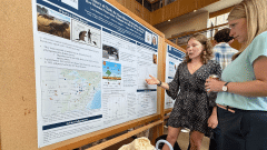 At a poster session, a student explains their research to a visitor.