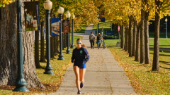 A runner on a sidewalk lined with bright yellow trees.
