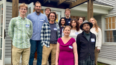 A group of college staff and students pose for a group photo on the porch of a house.