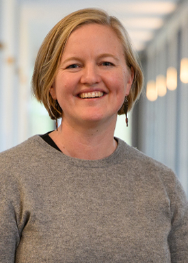 Portrait of person in beige sweater smiling at the camera.