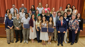 A group of people stand in front of a stage at an awards celebration..