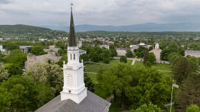 An aerial view of the Middlebury campus with a chapel spire in the foreground.