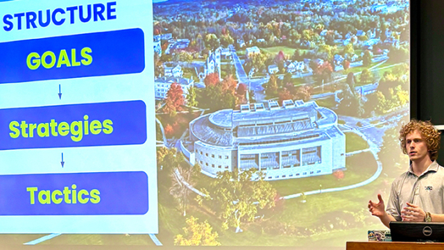 A student gives a presentation at a lectern in a classroom.