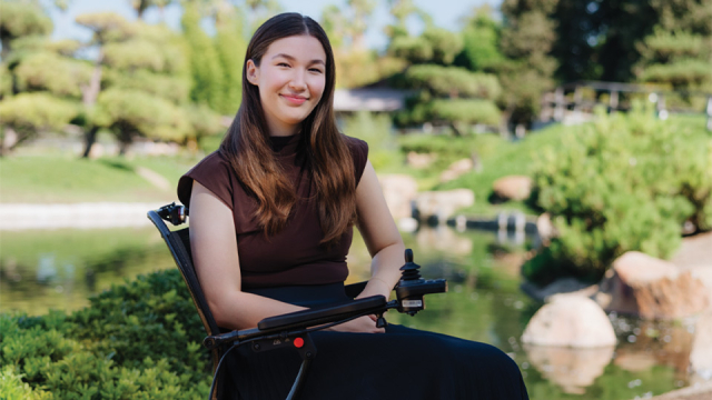 Photo of a woman sitting in a wheelchair and smiling.