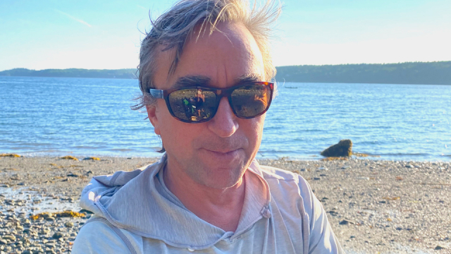 Photo of Professor Jeff Howarth standing on a beach wearing sunglasses