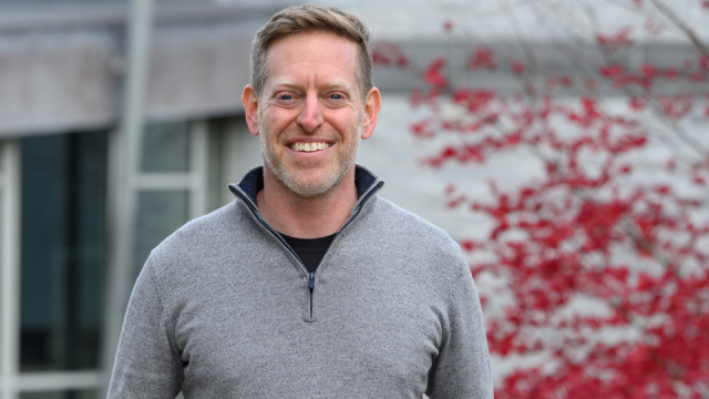Person in a gray zip sweater smiles at the camera