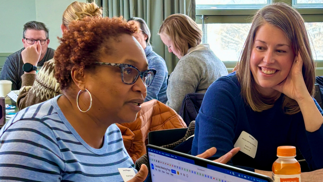 People engage in a discussion around a conference room table.