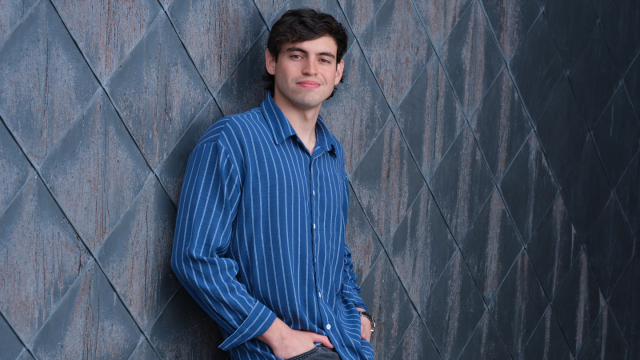 Photo of a student standing against a textured wall outside.
