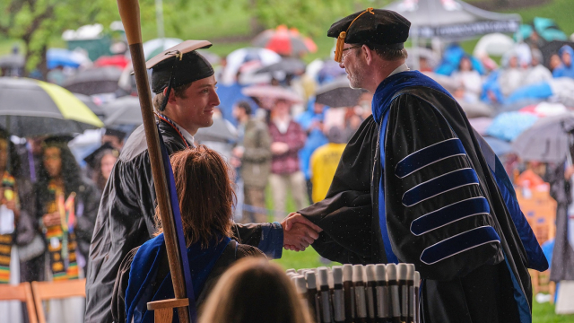 President Ian Baucom congratulates a Middlebury graduate on stage at Commencement.